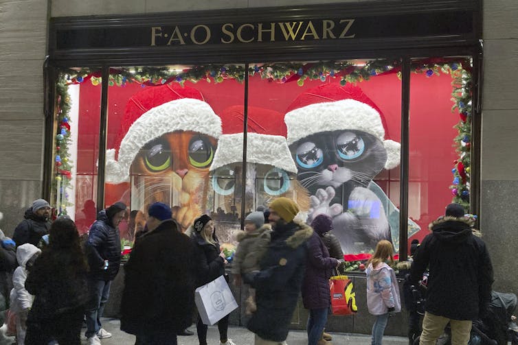 Bag-toting holiday shoppers walk in front of a window display at New York City's FAO Schwarz.