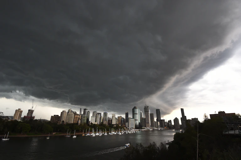 A grey landscape of a city and a river with a dark cloud above it