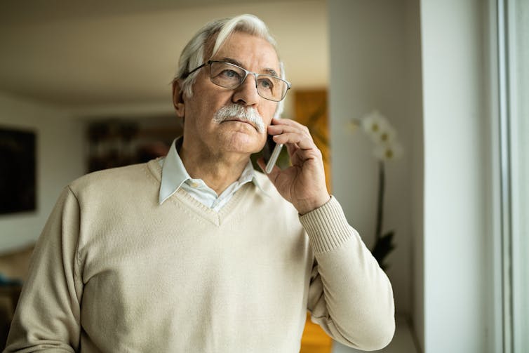 An older man speaks on the phone.