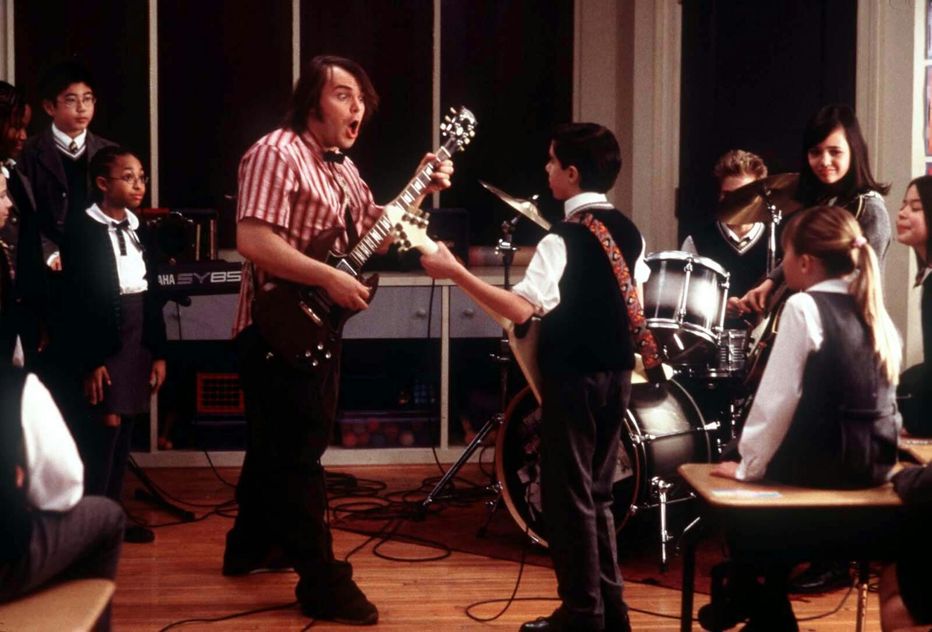 Jack Black's character Dewey Finn plays guitar with students in the classroom.