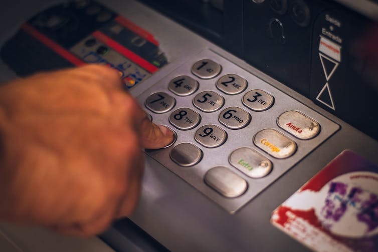 Close up of a hand entering pin code at an ATM
