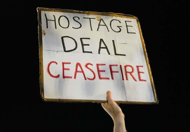 Hand holding placard saying "Hostage deal ceasefire"