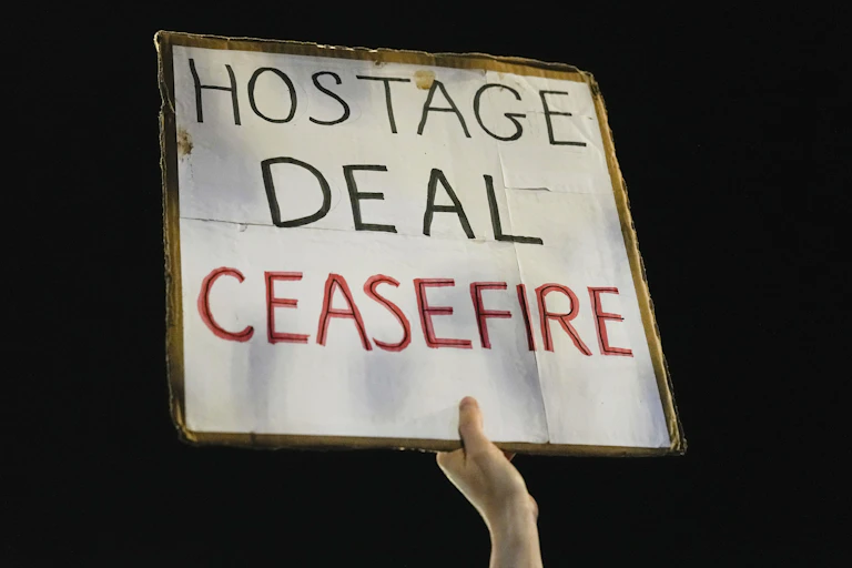 Hand holding placard saying "Hostage deal ceasefire"