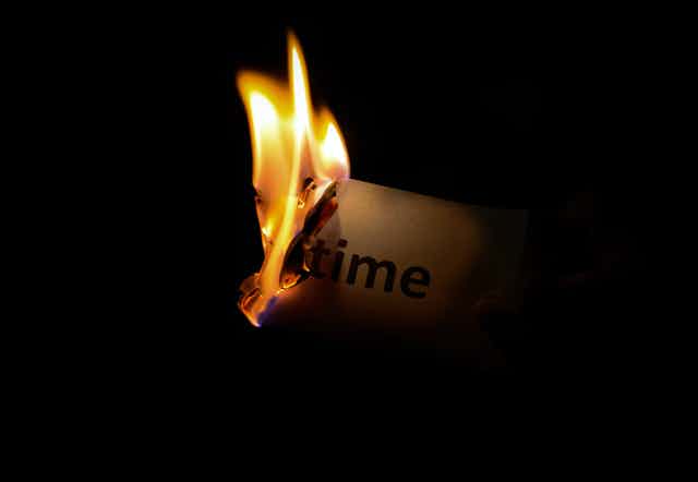 A piece of burning paper that reads "time" close up