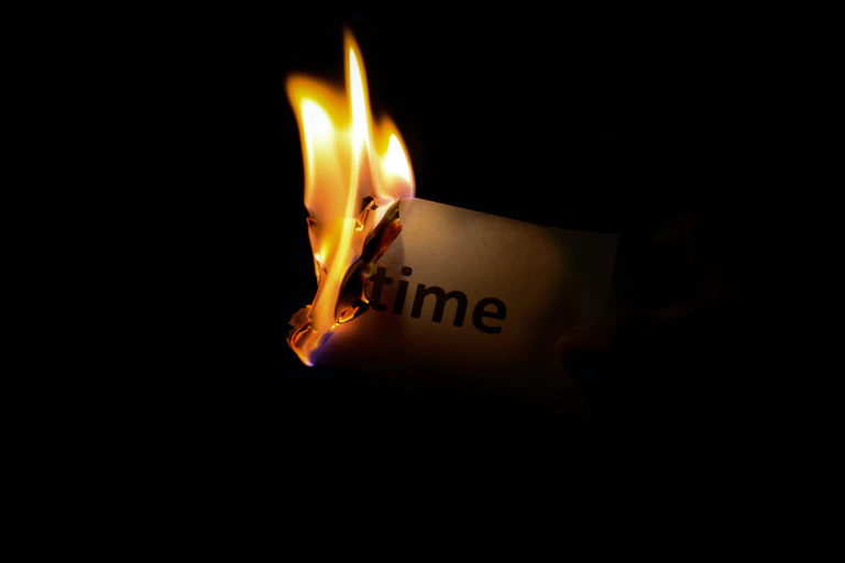 A piece of burning paper that reads "time" close up