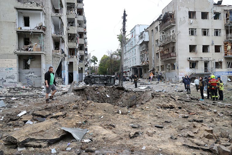 People next to a large crater caused by Russian bombing.