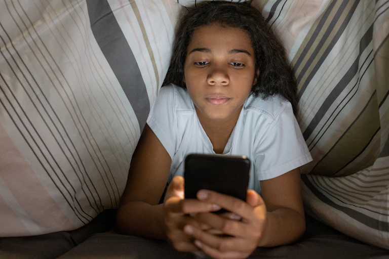 Girl in bed looking at mobile phone