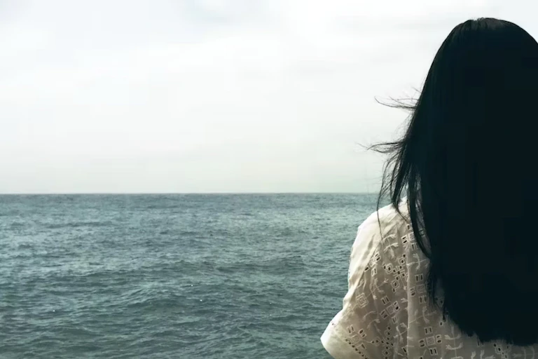 Une femme faisant face à la mer