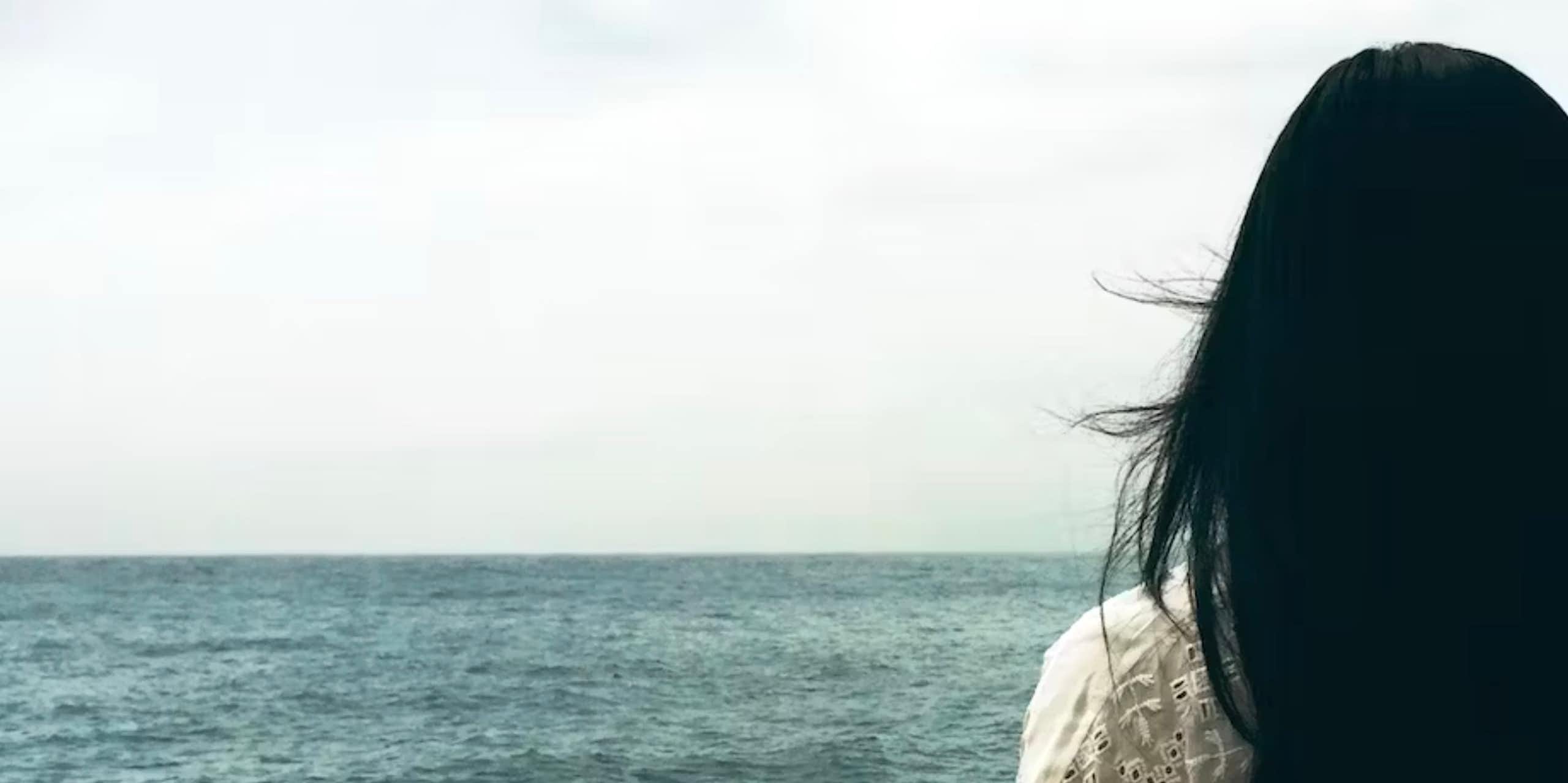 Une femme faisant face à la mer