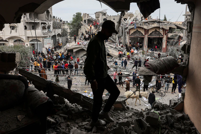 People are looking through rubble on streets near buildings that have been destroyed.
