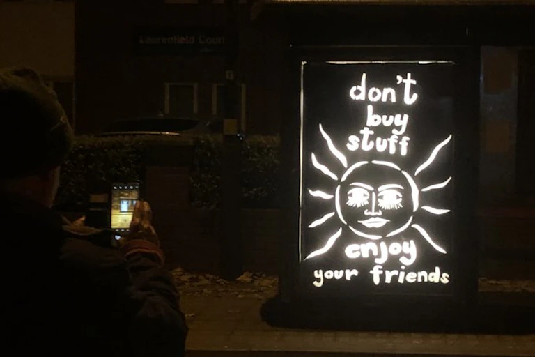 A billboard saying 'don't buy stuff, enjoy your friends'.