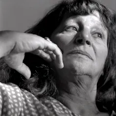 A black and white close up of a woman looking away from the camera with her hand to her face.