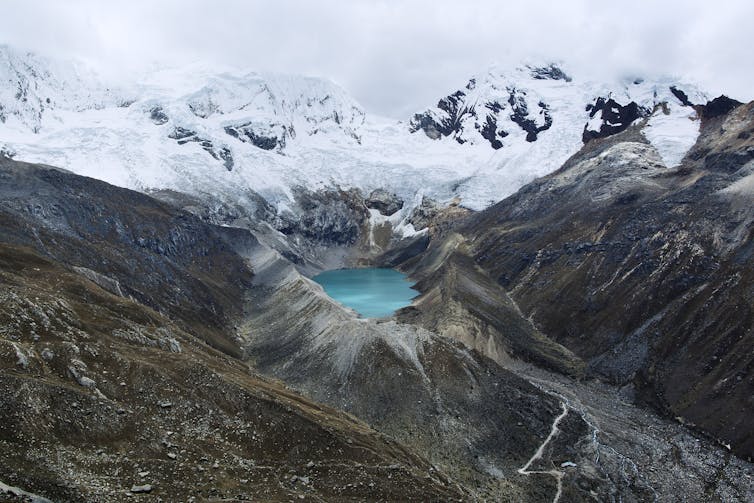 A high-altitude blue lake surrounded by snow-capped mountains.