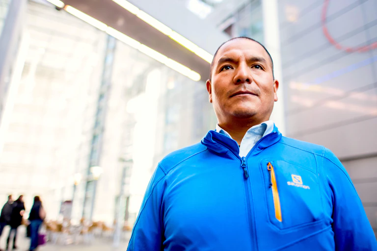 Peruvian man standing in front of a glass building