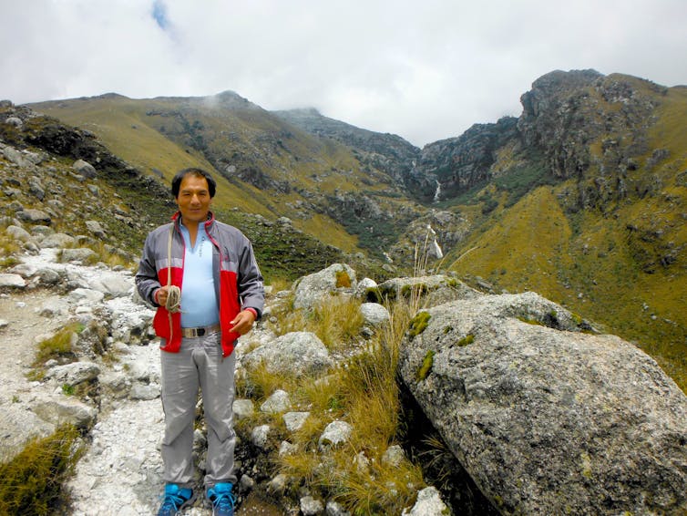 Peruvian man with grassy mountains behind.