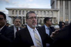 Le président élu du Guatemala marchant dans la rue, entouré d’hommes