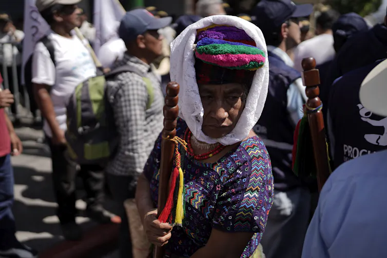 Une femme arborant des habits traditionnels guatémaltèques parmi une petite foule