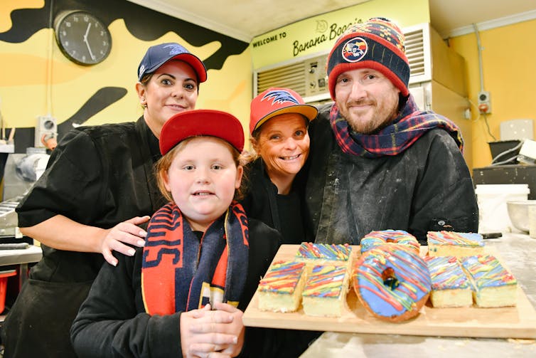 A family with donuts and vanilla slices in Crows colours.