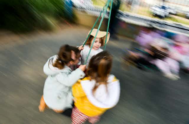 Three children play with a swing