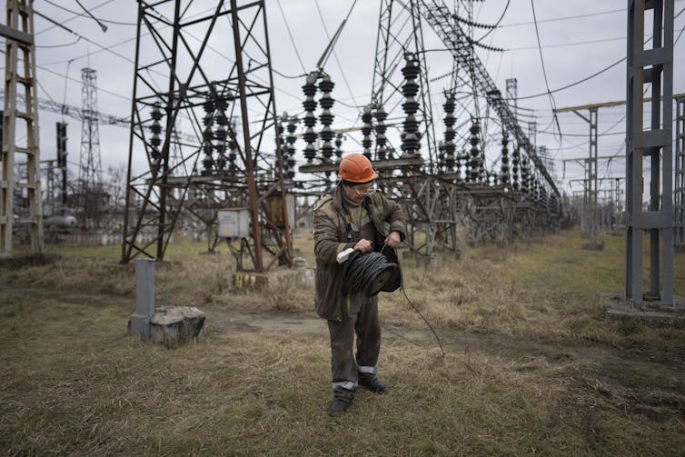 a man in protective gear surrounded by electricity poles