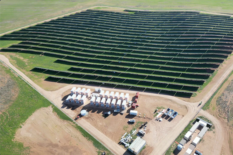 A field of solar panels seen from above with roads on two sides