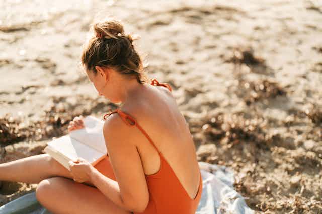 Photo of a woman reading a book and relaxing while vacationing by the sea