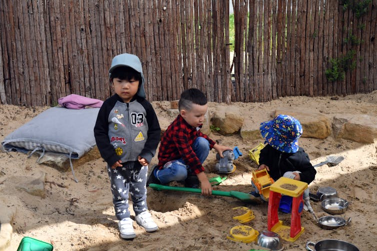 Small children play in a sandpit.