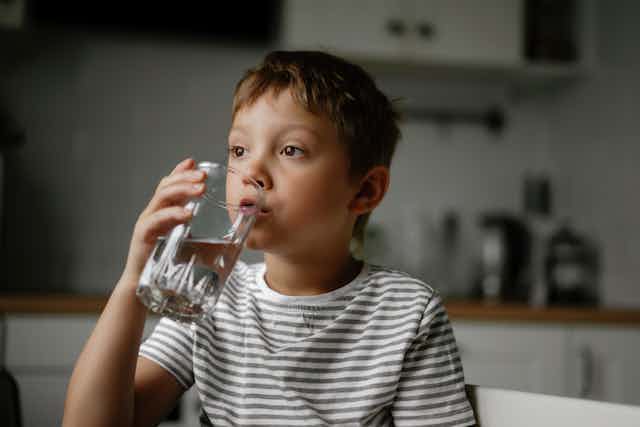 A boy drinking a glass of water.
