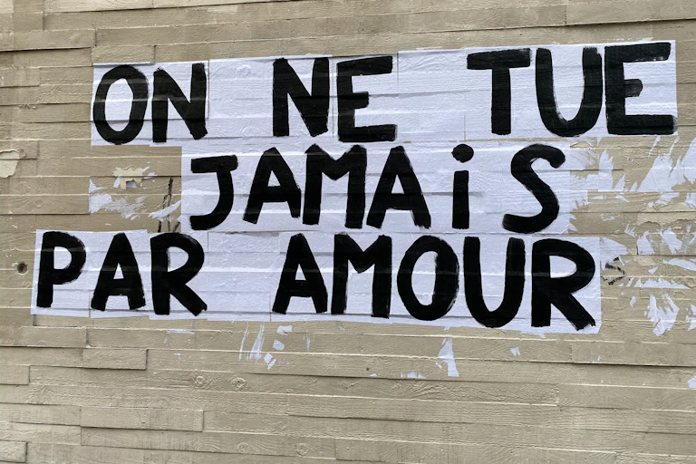 Collage sauvage avec la phrase "On ne tue jamais par amour" sur un mur de Paris.