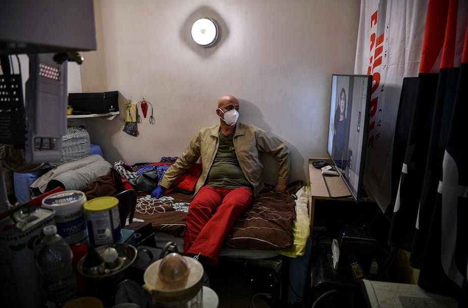 Un travailleur migrant palestinien, portant un masque de protection, est assis sur son lit dans sa chambre d'un immeuble abritant des travailleurs migrants à l'extérieur  à Paris le 8 mai 2020