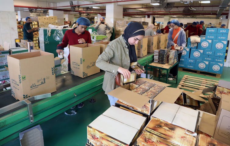 Egyptian volunteers pack boxes with food and other humanitarian aid in a warehouse.