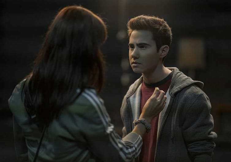 Un adolescente habla con una chica de espaldas a la cámara.