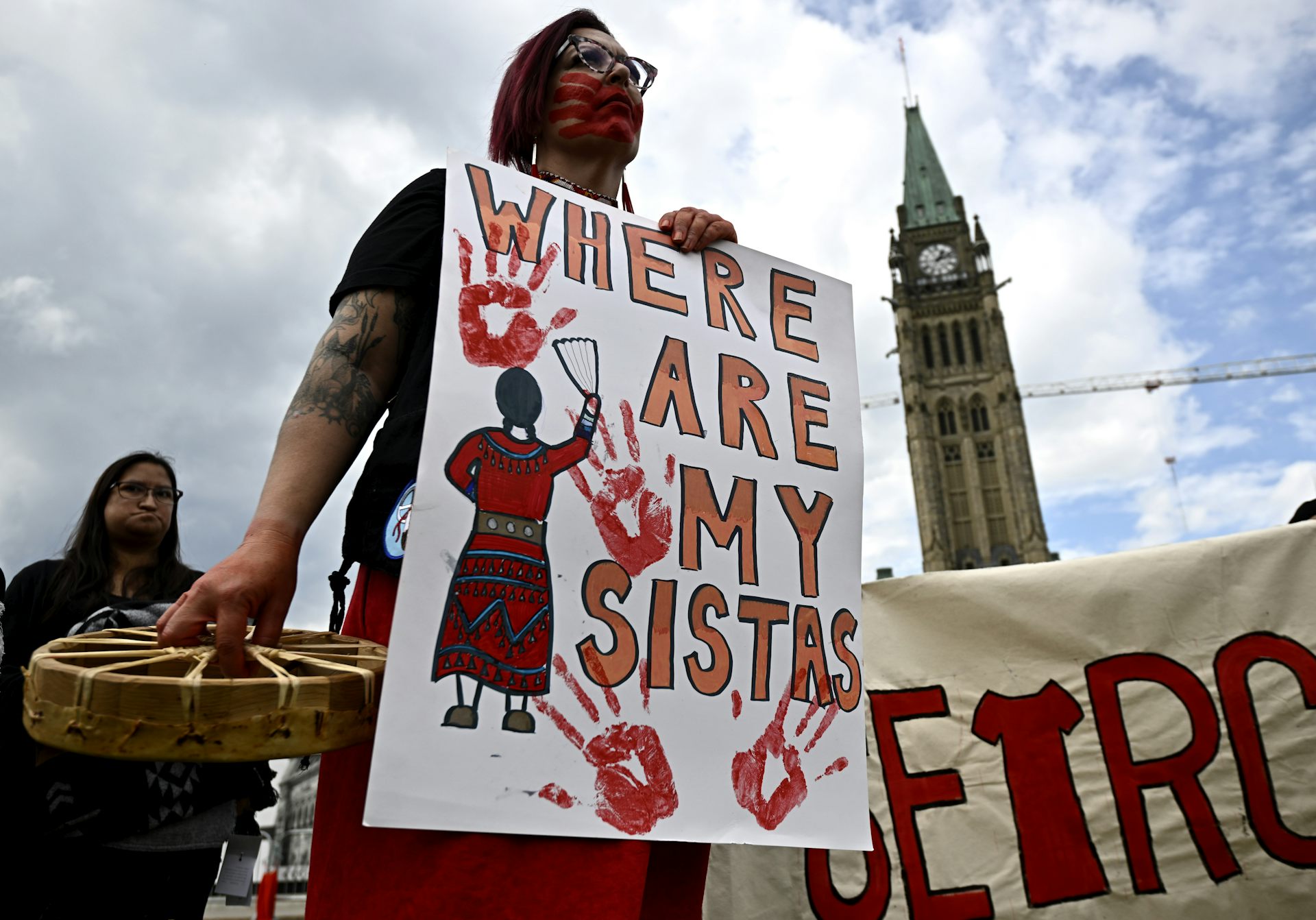 A woman seen with sign 'where are my sistas' printed with red hand marks.