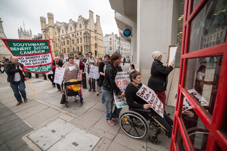 Protestors in wheelchairs with banners outside a building in London.