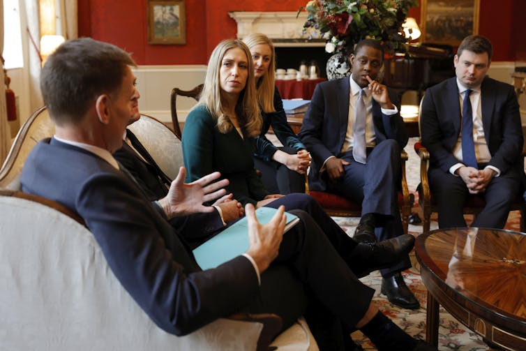 Chancellor Jeremy Hunt holding a copy of the 2023 autumn statement, speaking to a group of people.