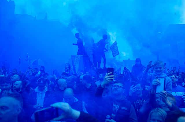 Everton fans gather in blue smoke.