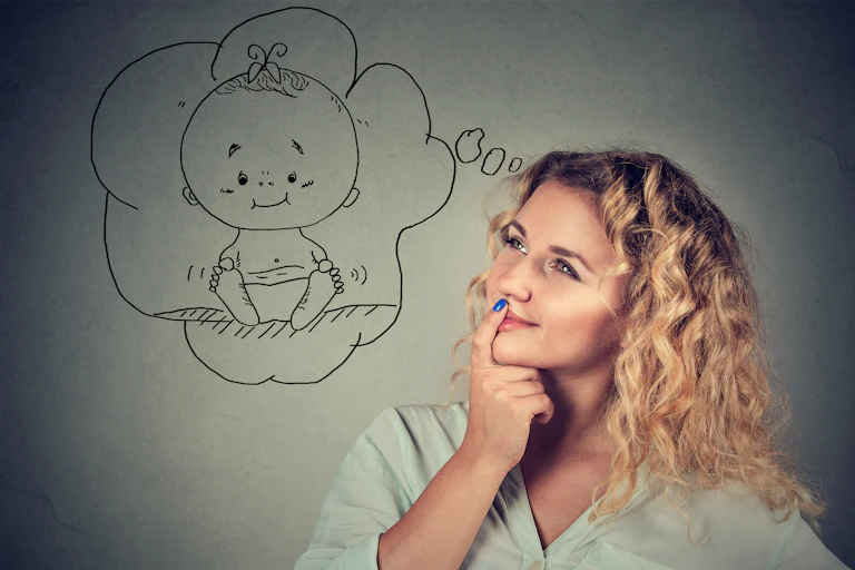 Young woman contemplating having a child posing against a grey background.