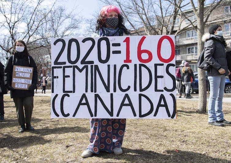 A woman holds a sign that says 2020: 161 Feminicides.