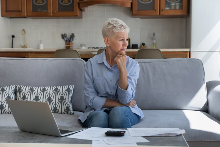 Woman looking worried with bills and calculator.