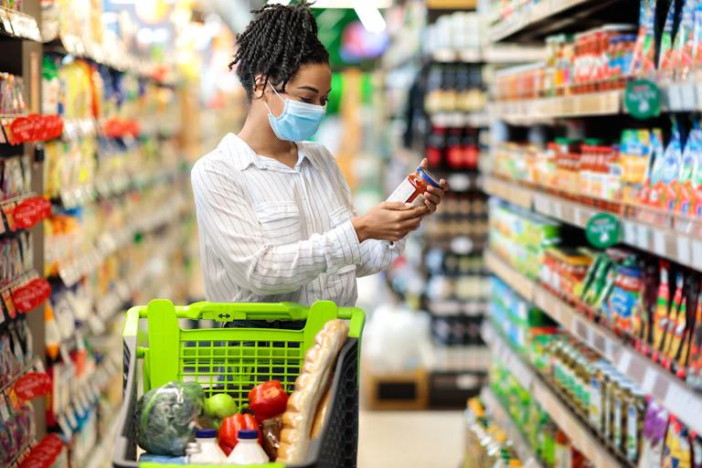 African-Australian woman looks at the label of pasta sauce at the supermarket