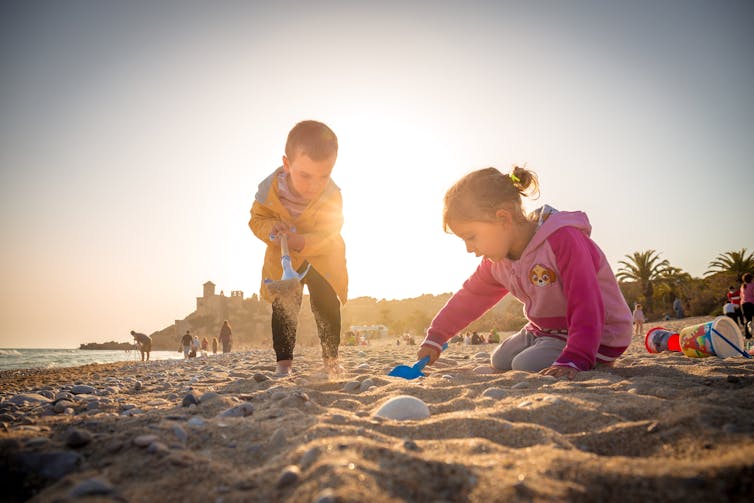 Two children play in the sand at a beach.