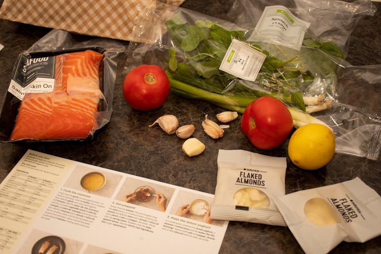 contents of meal kit delivery with packets and foods on bench