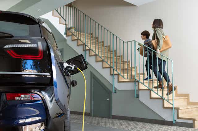 mother and son walking up stairs from garage with EV charging in foreground
