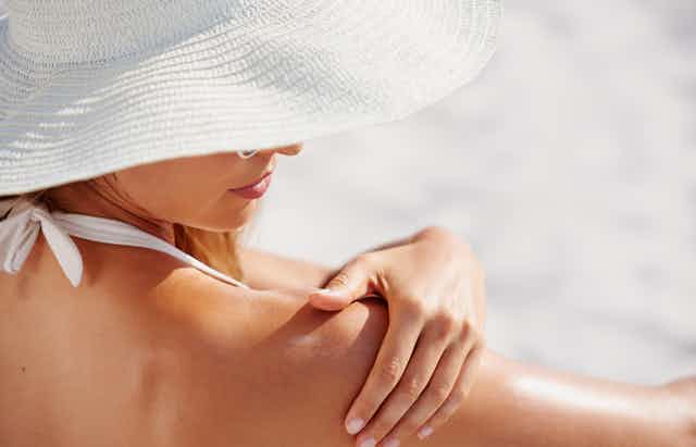 woman applies sunscreen to shoulder