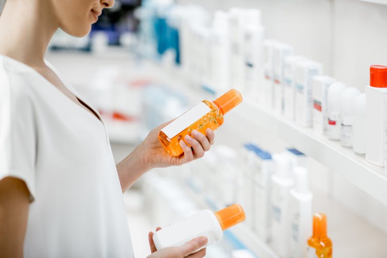woman compares sunscreen labels in pharmacy