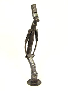 a metal sculpture of an elongated female figure with traditional African attire.