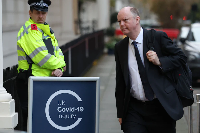 Chris Whitty walking into a building past a sign that says UK covid-19 inquiry.