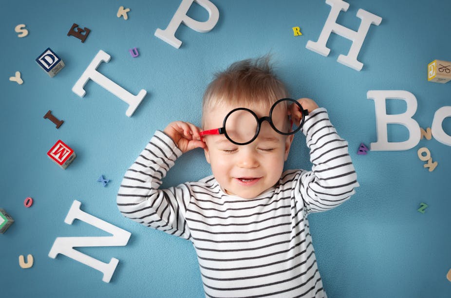Enfant d'un an, allongé sur fond bleu, avec des lunettes et des lettres