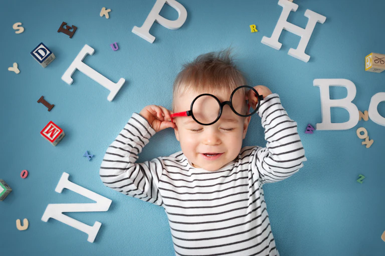 Enfant d'un an, allongé sur fond bleu, avec des lunettes et des lettres