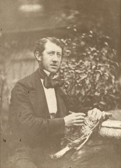 Black and white portrait of man sat down in formal dress.